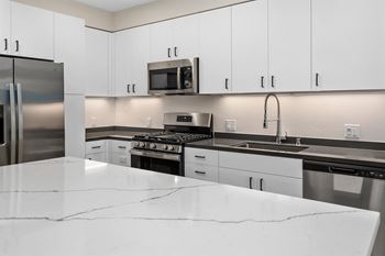 an all white kitchen with stainless steel appliances and white counter tops